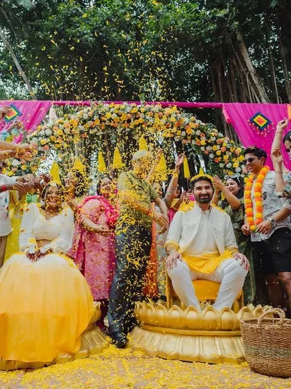 A candid moment of pure joy as the couple is showered with flower petals during their Haldi ceremony. The vibrant decor perfectly matches the happy mood.