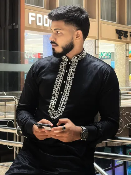 A client looking thoughtful in his black hand-embroidered kurta, captured in a candid moment.