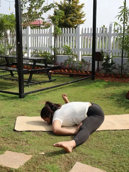 A twisting lizard pose, working on hip flexibility and spinal rotation in a beautiful garden setting.