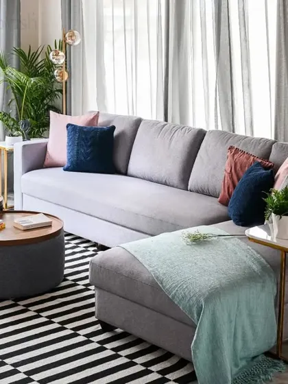 A close-up of the comfortable L-shaped sofa, styled with colorful cushions. The round nesting coffee tables are a practical and stylish choice for a modern living room.