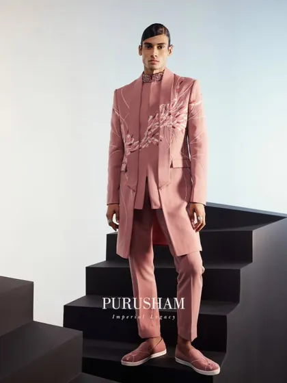 This peach-infused traditional wear is designed to embody delicate beauty. The long jacket with its clean lines and subtle embroidery is a sophisticated choice for a modern groom.