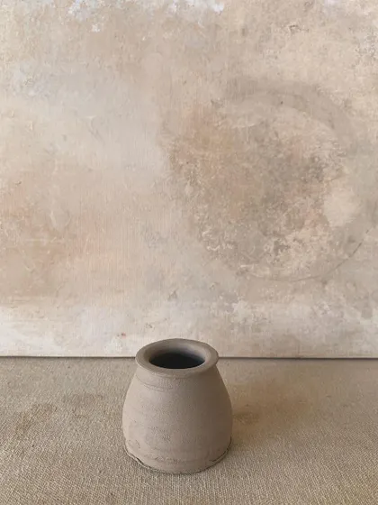 A small, raw pot, perfectly centered and ready for its next stage.