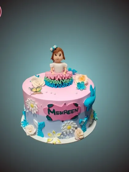 A sweet and simple cake with a pink and blue ombre effect, topped with a cute fondant girl figurine.