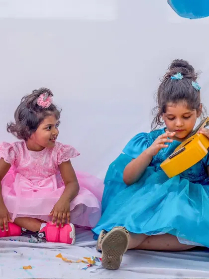 A sweet moment between two sisters, both dressed in my elegant party frocks. One wears a soft pink tulle dress while the other shines in a beautiful blue gown, creating a harmonious pastel palette.