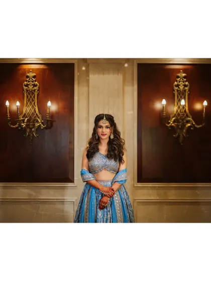 A symmetrical and elegant portrait of the bride standing between two ornate wall lamps.