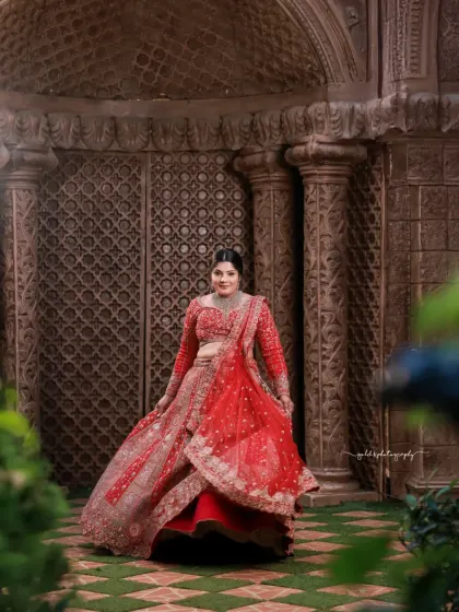 This shot captures the bride amidst lush greenery, with the vibrant red of her lehenga standing out beautifully. The movement in the skirt adds a dynamic and celebratory feel.