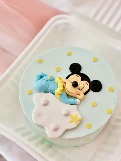 A mini "bento" cake featuring a sleeping baby Mickey Mouse. This small, personal-sized cake is perfect for intimate celebrations or monthly milestones.