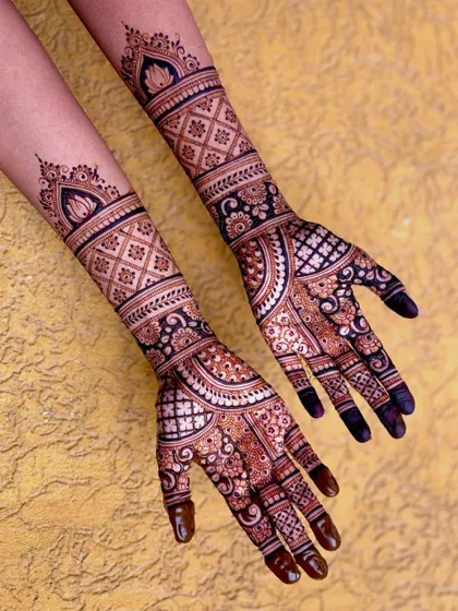 A top-down view of Shifna's bridal mehendi, showing the lotus toppers and detailed arm bands.