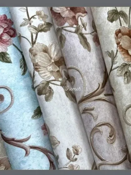 A close-up of several rolls of classic floral scroll wallpaper in different color palettes.