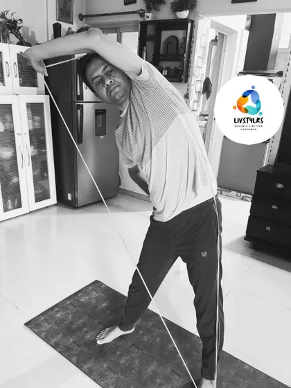 This black and white photo captures a client in a dynamic side stretch using a resistance rope, highlighting the lines of the body and the intensity of the pose.