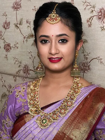 A classic portrait of a South Indian bride. The makeup is timeless, with a bold red lip and defined eyes, a look that will be a cornerstone of your bridal makeup skills.