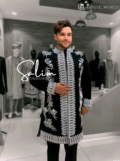 A client wearing a black open-front jacket with heavy silver embroidery over a black kurta. The layering adds depth and formality to the ensemble.