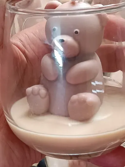 A close-up of a single teddy bear jar candle, showing the cute details of the bear sculpture.