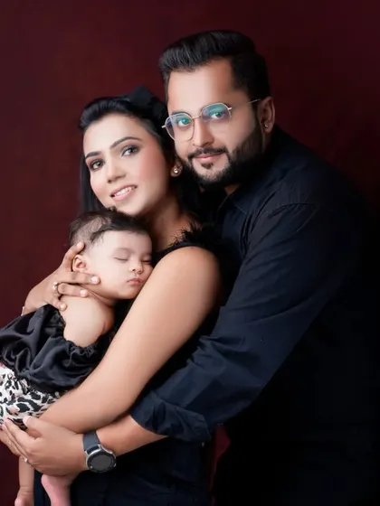 A beautiful family of three, wrapped in a loving embrace. This studio portrait captures the peace of a sleeping newborn held securely by her parents.