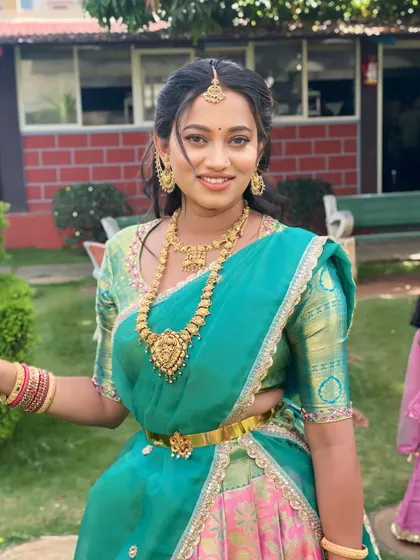 A beautiful, happy client ready for her event. The makeup is classic South Indian style, with defined eyes and a radiant finish that complements her half-saree.
