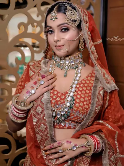 A medium portrait showcasing the bride's complete upper body look. Her pose highlights the intricate hand jewellery (hath phool) and the detailed work on her blouse.