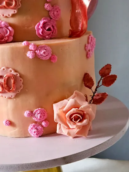 A detail shot of the base of the mother-daughter cake, showing the smaller, delicate sugar flowers and the "50" marker for the mother's milestone birthday.