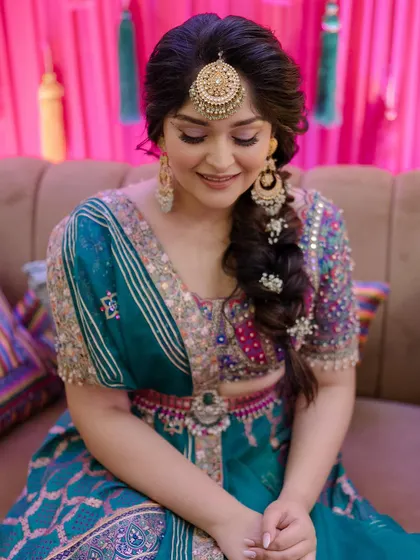 A closer look at the bride with her beautiful side braid, showing how it complements her maang tikka and colorful outfit.