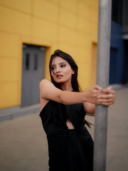 A duplicate of image 355, this portrait against a yellow wall uses a metal pole as a prop to create a modern and graphic fashion shot.