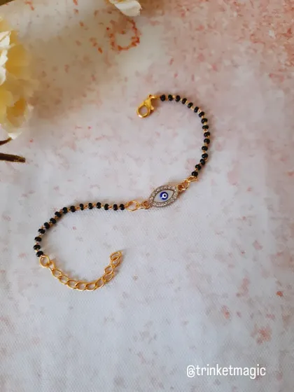 Protection meets elegance with this evil eye mangalsutra bracelet. The traditional black beads are paired with a sparkling evil eye charm, making it a perfect modern accessory.
