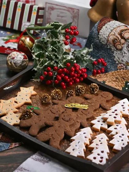 A festive tray of our Christmas cookies. It features classic gingerbread men, jam-filled tree cookies, and star-shaped biscuits, perfect for sharing with family and friends.