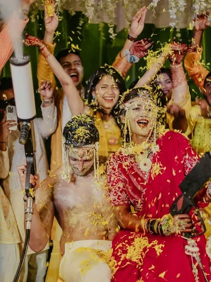 A high-energy shot of the couple being showered with petals and smoke from confetti cannons.