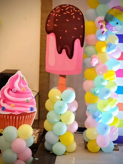 Fun props at the Candyland party, including a giant ice cream cone and cupcake made from balloon sculptures and cutouts.
