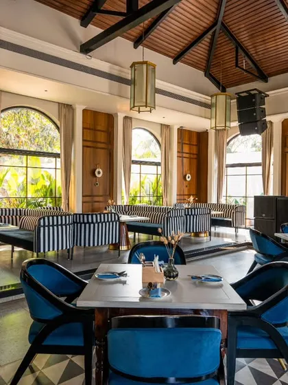 This shot captures the daytime ambiance at Vamos Experience, with natural light flooding in through the large arched windows. It highlights the airy, open feel of the space and its connection to the green outdoors.