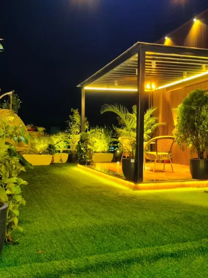 A ground-level view of the completed Model Town project, showcasing the lush artificial turf and the warm glow of the garden lights.