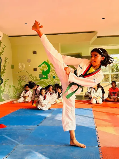 A student demonstrates a perfect high side kick, showcasing excellent form, balance, and flexibility.