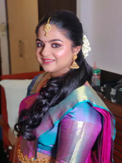 A smiling portrait of Pavitra. Her soft glam makeup and side-parted hairstyle create a fresh and youthful look for her engagement.
