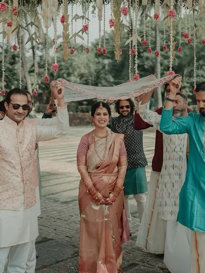 The bride's traditional entrance, walking under a delicate veil held by her brothers.