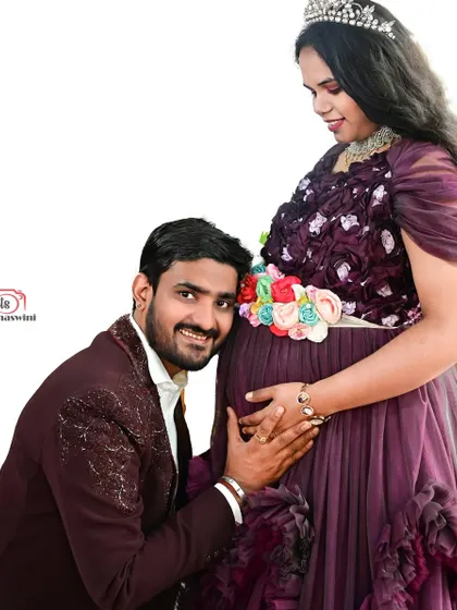 A sweet and intimate photo from a maternity shoot. The dad-to-be listens to the baby bump, while she looks radiant in our purple gown.
