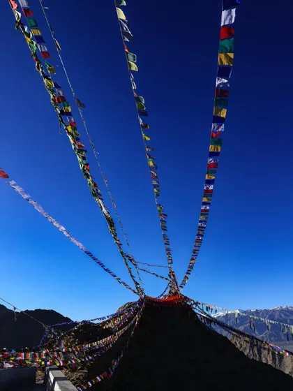 Tibetan prayer flags fluttering in the wind against a clear blue sky, a common and uplifting sight on our mountain expeditions.
