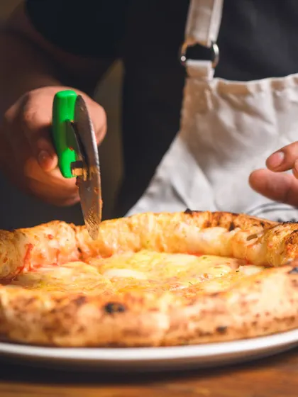 The final cut. We use scissors to preserve the puffy crust and ensure a clean slice every time.