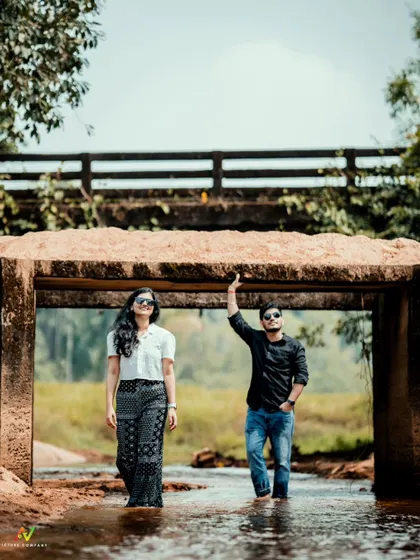 A stylish shot of a couple standing under a small bridge in a stream, looking cool and confident.