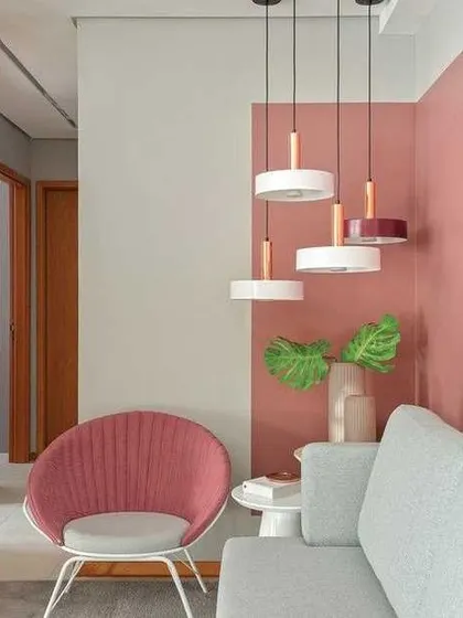 In this living area, a vertical colour block of dusty rose adds warmth and visual interest behind the seating. This method helps to break up a long wall and coordinate with the room's furniture and decor.