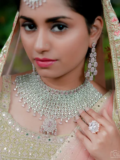 A close-up of a bride wearing a stunning pastel pink AD set. The intricate design of the choker and the large statement ring create a look of modern luxury.