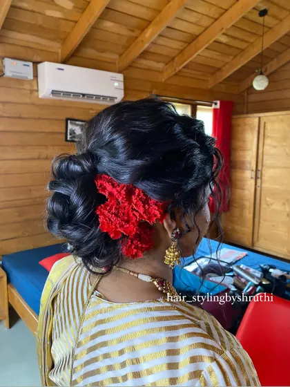Another angle of the romantic low bun with red flowers, showing the texture and softness of the updo. This is a great style for bridesmaids or wedding guests.