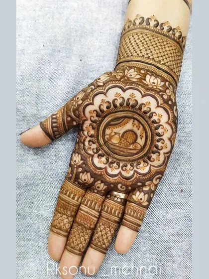 This is a classic Karwa Chauth design, with a central mandala showing the traditional scene of a woman with the sieve and pot. It’s a beautiful way to honor the rituals of the day.