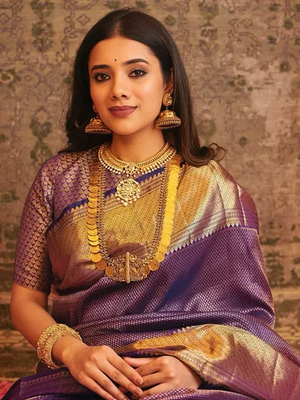 A full portrait of the bride, seated, exuding confidence and grace. The entire look is a beautiful example of classic South Indian bridal style.