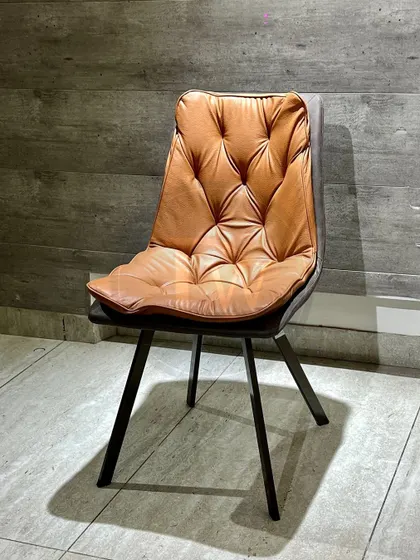 This dining chair features a striking tufted cushion in rich tan leatherette, offering both a unique look and exceptional comfort. It's a piece that adds warmth and texture to your dining area.