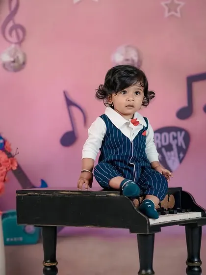 A little musician sitting on a piano. The striped suit and bow tie add a touch of formal charm to this fun, musical theme.