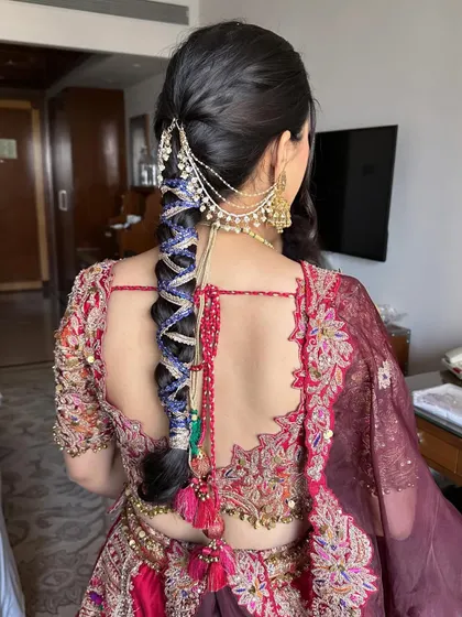 A vibrant and playful hairstyle perfect for a Mehendi or Haldi ceremony. This look features a thick braid intricately woven with colorful threads and finished with bright tassels and traditional hair jewellery, reflecting a fun and festive mood.