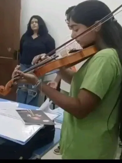 A violin student receives guidance from her instructor during a practice session. Our teachers work closely with students to help them perfect their posture, bowing technique, and intonation.