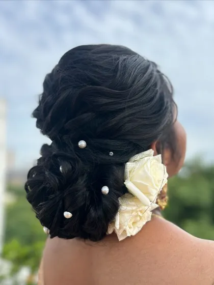 A side view of the textured bun, adorned with classic white roses for a touch of elegance.