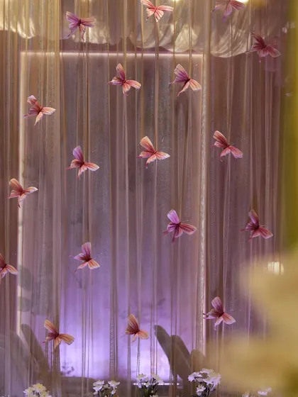 Handcrafted butterflies seem to float in mid-air against a backdrop of sheer curtains. This whimsical detail from our 'Midsummer Dream' reception added a sense of magic and movement to the decor.