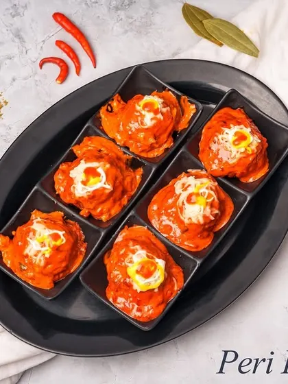 These chicken meatballs are packed with spicy peri-peri flavor. They are cooked until tender and served in individual bowls, topped with a dollop of cream and cheese for a rich finish.
