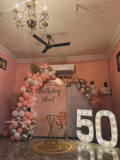 The complete setup for a beautiful 50th birthday surprise at home. The warm pink tones, elegant chandelier, and sparkling lights created a magical atmosphere.