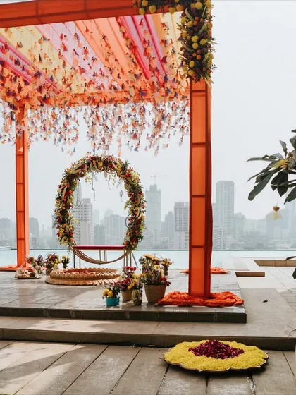 A stunning sundowner Haldi setup on a rooftop, using a fusion of colors to break the stereotype of a yellow-only theme.